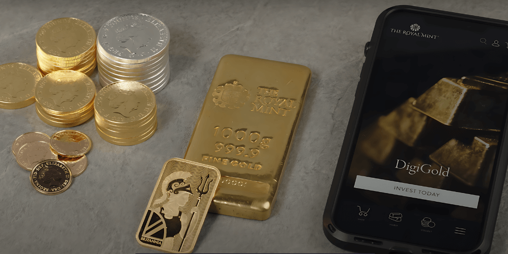 A selection of gold bars and coins alongside a mobile phone showing a digital gold platform 1000x500.png